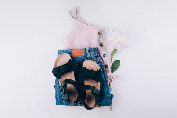 Sommermode-Outfit mit Top, Jeanshose, schwarzen Sandalen. Weibliche Reisekleidung. Draufsicht, flache Lage - Foto, Bild
