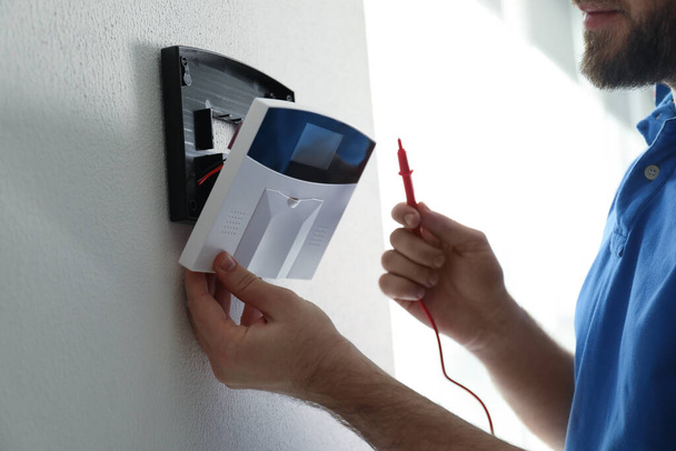 Man installing home security system on white wall in room, closeup - Foto, Imagem