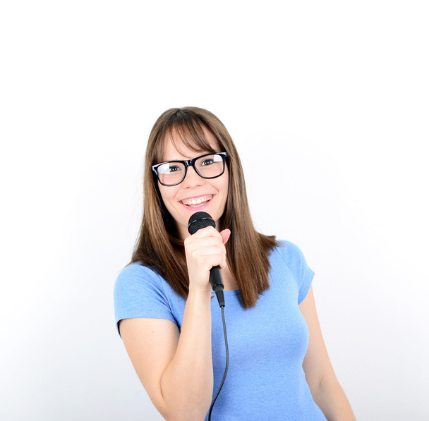 Portret van een jonge vrouw met microfoon tegen witte backgro - Foto, afbeelding