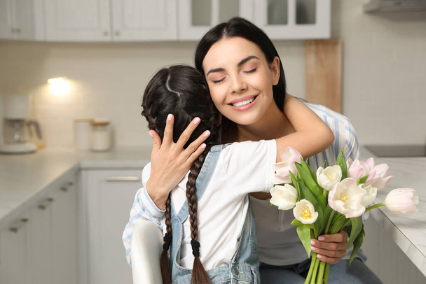 Little daughter congratulating her mom in kitchen at home. Happy Mother's Day - Foto, afbeelding