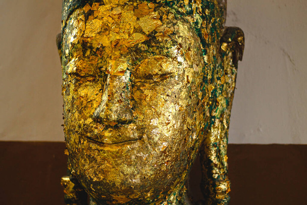 Κεφάλι αγάλματος του Βούδα καλυμμένο με φύλλα χρυσού που προσφέρει στο Wat Phutthaisawan στην Ayutthaya, Ταϊλάνδη - Φωτογραφία, εικόνα