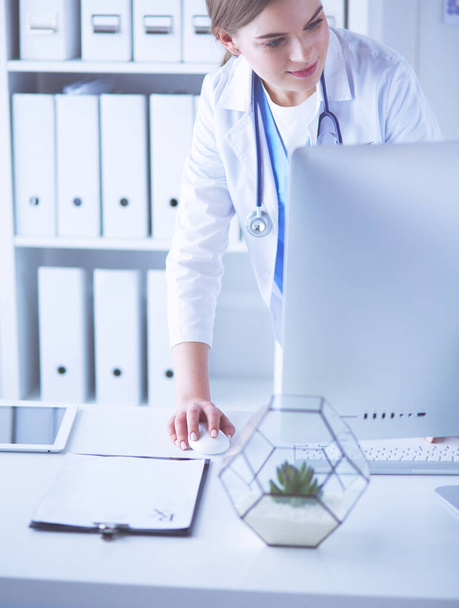 Młoda kobieta lekarz w pracy, wskazując na komputer w biurze szpitalnym. - Zdjęcie, obraz