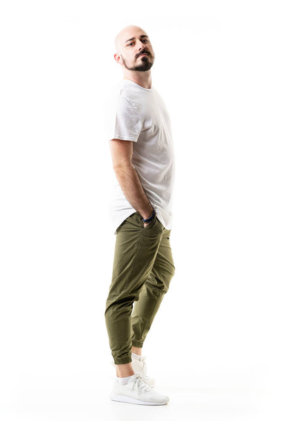 Raffreddare moderno elegante giovane rasato uomo calvo posa con le mani in tasca. Lunghezza totale del corpo isolata su sfondo bianco - Foto, immagini