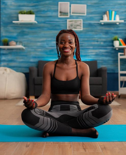 Porträt einer lächelnden schwarzen Frau, die zu Hause Yoga praktiziert - Foto, Bild