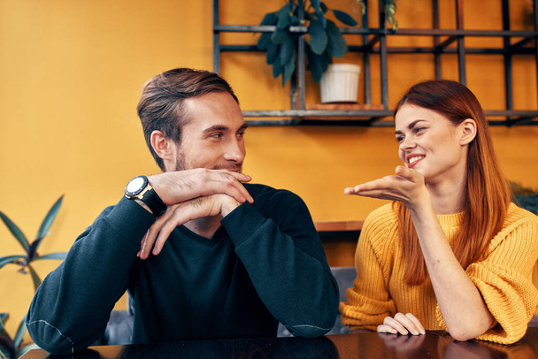alegre hombre y mujer haciendo gestos con las manos y sentados en una mesa en un café comunicación amigos una taza de café - Foto, Imagen