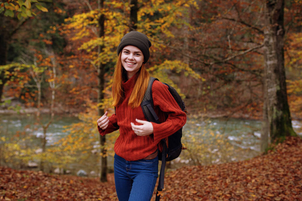 жінка в осінньому парку з опалим листям і рюкзаком на її задній річці на задньому плані
 - Фото, зображення