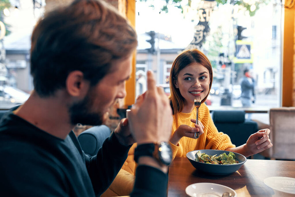 hombres y mujeres emocionales en una mesa en un café divertido pareja casada comida ensalada - Foto, imagen