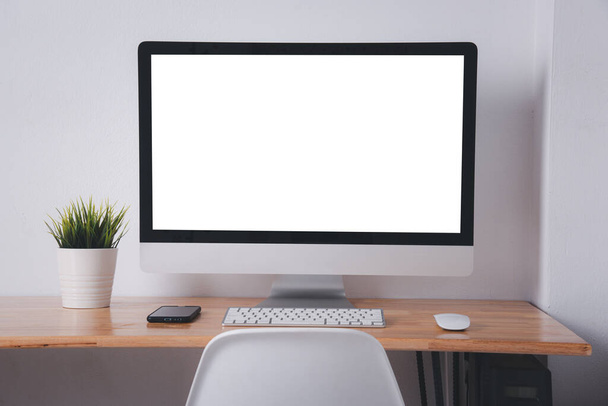 Computer monitor with white blank screen on the business desk with wireless mouse, keyboard at home office over white wall background, Photo of equipment contemporary workspace - 写真・画像