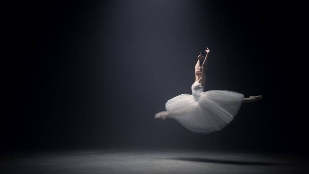 Hermosa mujer volando en vestido de ballet en el escenario. Bailarina bailando adentro. - Foto, imagen