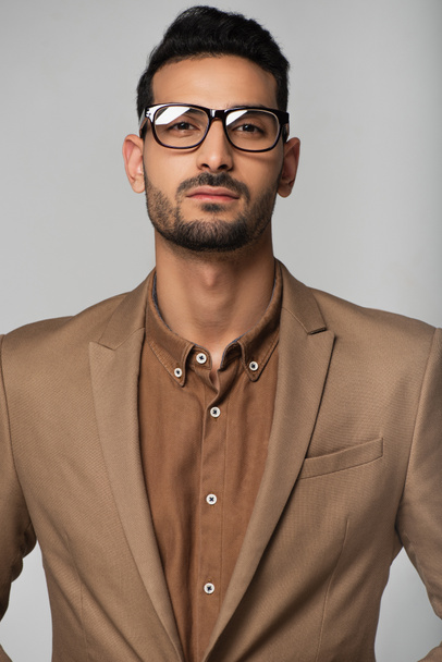 Muszlim üzletember szemüvegben elszigetelt kamerát néz a szürkén.  - Fotó, kép