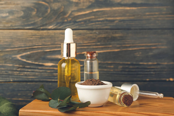 Сухий порошок хни в мисці та пляшки ефірної олії на дерев'яному фоні
 - Фото, зображення