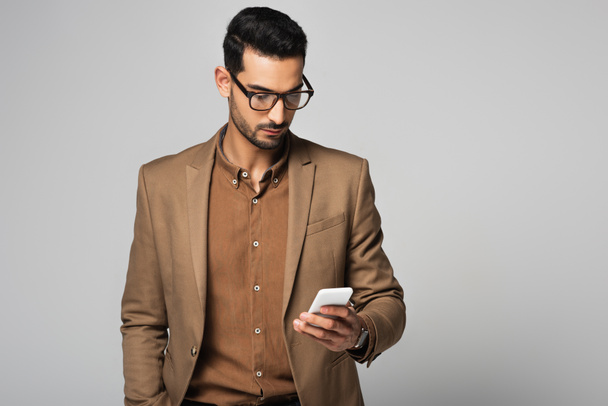 Arabian businessman using smartphone isolated on grey  - Photo, Image
