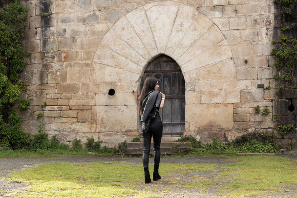 jeune femme brune vêtue de vêtements en cuir marche - Photo, image