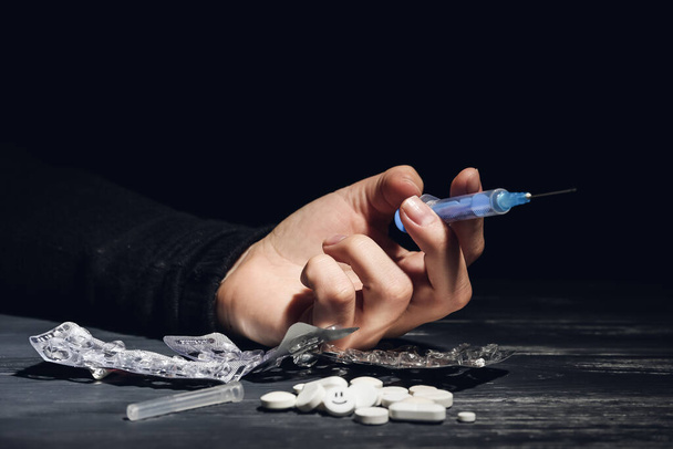Junkie with syringe and pills and table, closeup - Foto, immagini