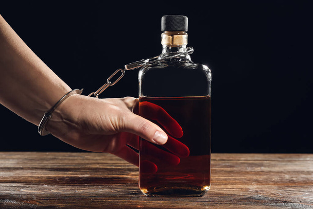 Nainen käsiraudoissa viskipullossa. Alkoholismin käsite - Valokuva, kuva