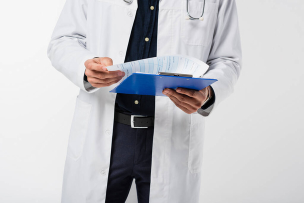 Cropped view of doctor holding clipboard isolated on grey  - 写真・画像