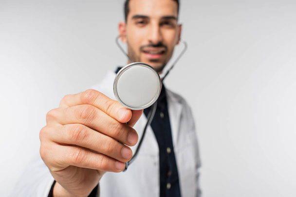 Stethoscope in hand of blurred muslim doctor isolated on grey  - Fotoğraf, Görsel