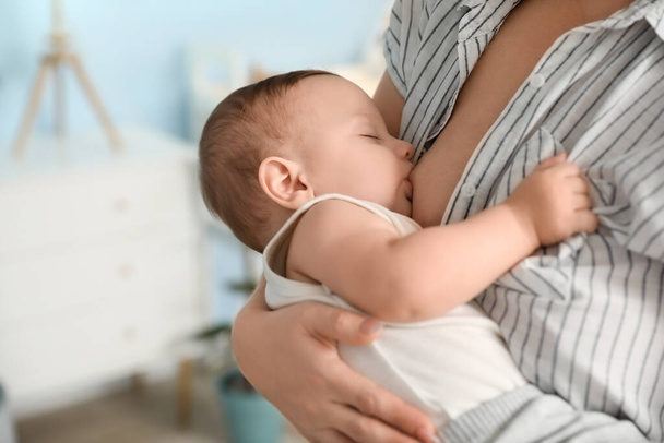 Young woman breastfeeding her baby at home, closeup - Foto, afbeelding