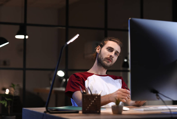 Handsome man working in office at night - Photo, Image