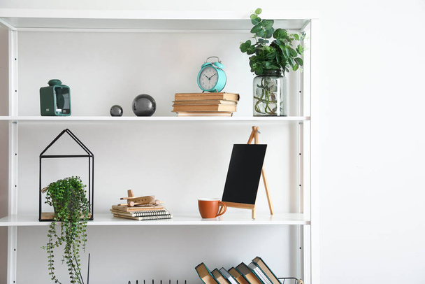 Modern book shelf with decor near light wall - Foto, imagen
