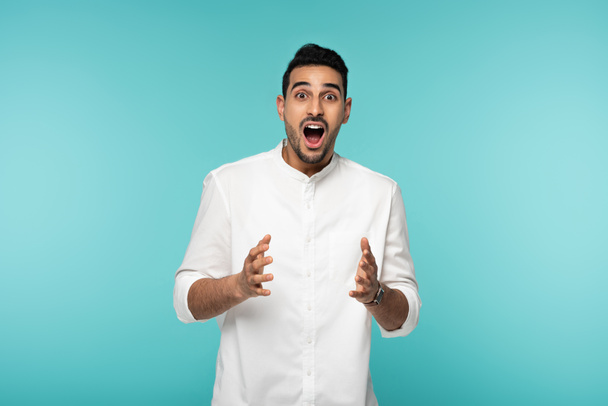 Excited muslim man in white shirt isolated on blue  - Foto, afbeelding