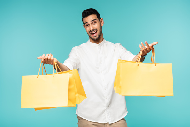 Hombre musulmán feliz sosteniendo gas de compras con compras aisladas en azul  - Foto, Imagen