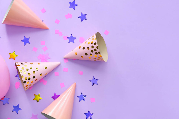 Party hats and confetti on color background - Фото, изображение