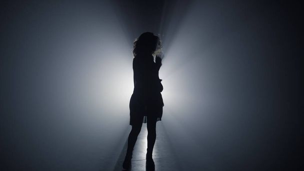 Chica silueta bailando en la oscuridad. Mujer despreocupada divirtiéndose en el espacio oscuro. - Foto, Imagen