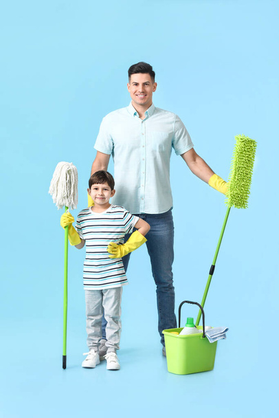 Vater und Sohn mit Putzmitteln auf farbigem Hintergrund - Foto, Bild