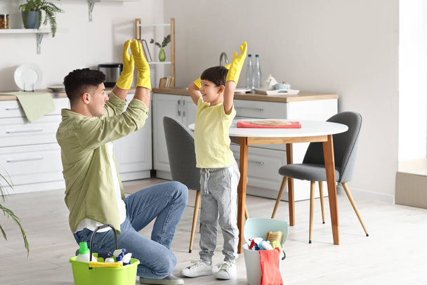 Padre e hijo con artículos de limpieza en la cocina - Foto, Imagen