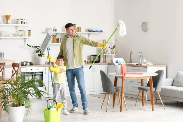 Father and son with cleaning supplies in kitchen - Fotoğraf, Görsel