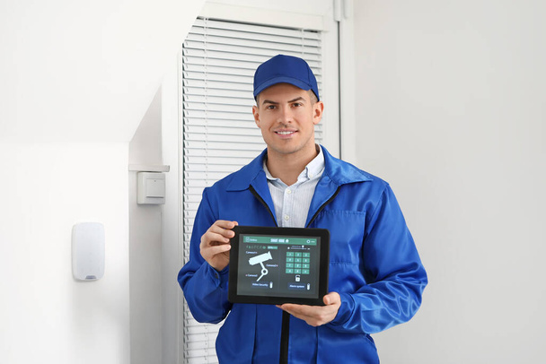 Worker with tablet computer checking alarm system indoors - Photo, Image