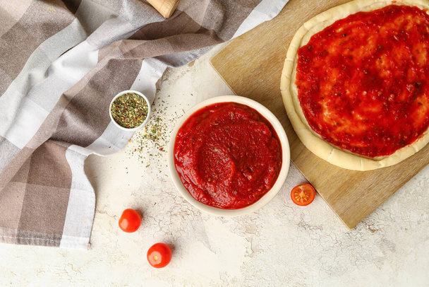 Pâte à pizza avec sauce tomate savoureuse sur fond clair - Photo, image