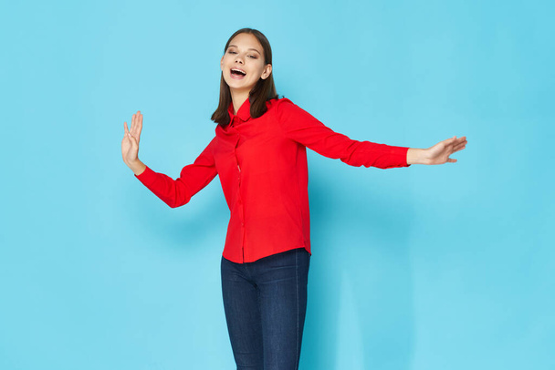 cheerful woman red shirt gesturing with hands blue background - 写真・画像