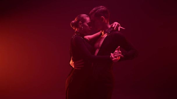 Elegant dancers posing camera dark studio. Elegant dance couple holding hands. - Photo, Image