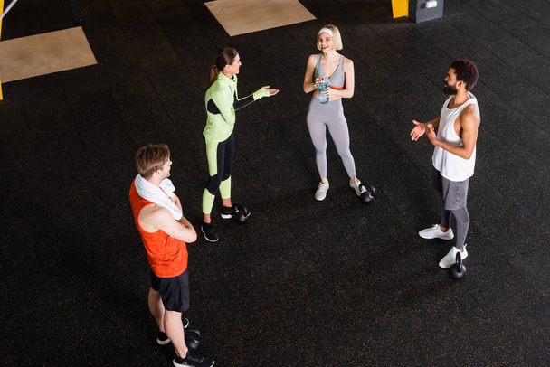 high angle view of smiling interracial people in sportswear talking in gym - Photo, Image