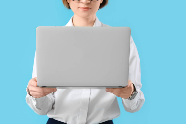 Female programmer with laptop on color background - Фото, изображение