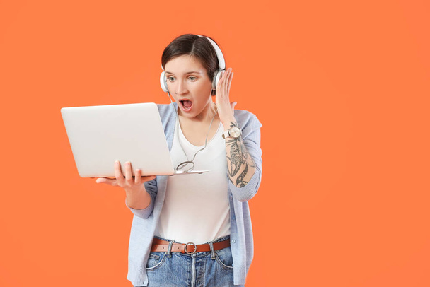 Geschokte vrouwelijke programmeur met laptop op kleur achtergrond - Foto, afbeelding