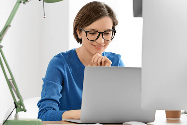 Female programmer working with laptop in office - Photo, image