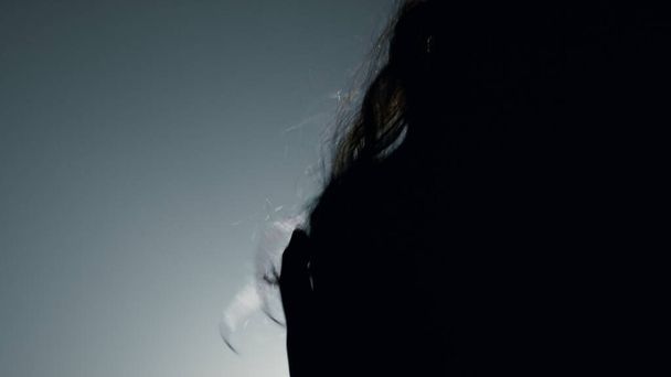 Silhouette sexy model moving head flying hair indoors. Beautiful girl dancing - Фото, зображення