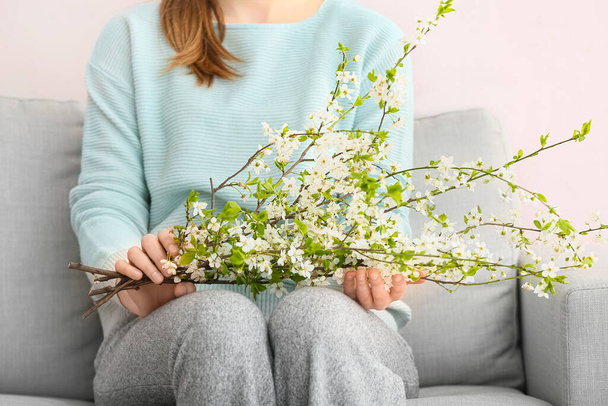 Donna con bellissimi rami fioriti sul divano in camera - Foto, immagini