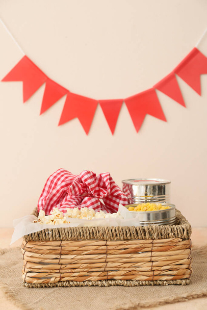 Корзина с вкусной попкорн, кукуруза и пакет на цветном фоне. Празднование праздника Феста Джунина (июнь) - Фото, изображение