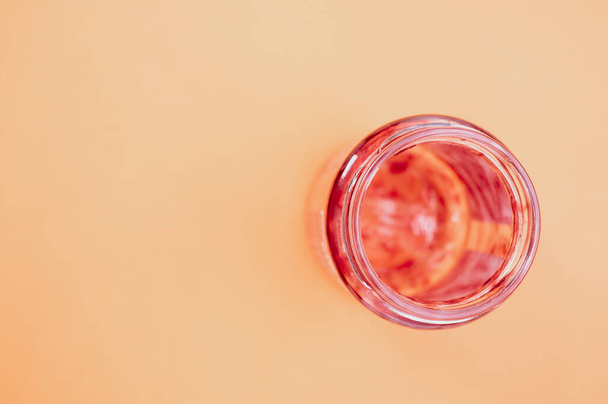 A top view of an empty strawberry jam jar isolated on peach background - 写真・画像