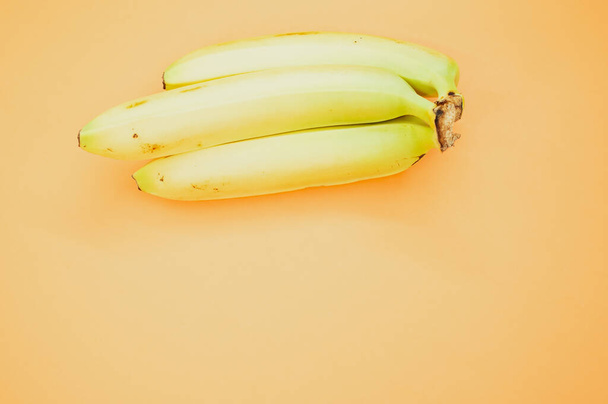 A high angle shot of ripe bananas isolated on light orange background - Foto, afbeelding