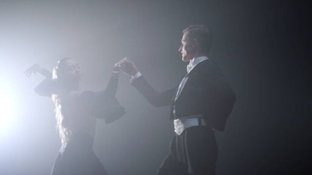 Professional dancers holding hands dancing. Ballroom couple performing waltz - Фото, изображение