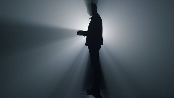 Karanlıkta dua eden uzun boylu bir adam. Silüet inananlar el yakarışları. - Fotoğraf, Görsel