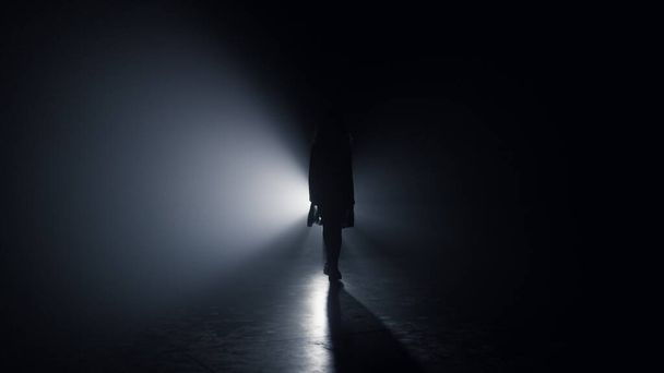 Menina silhueta caminhando escuridão. Mulher indo direto na câmera fundo escuro - Foto, Imagem
