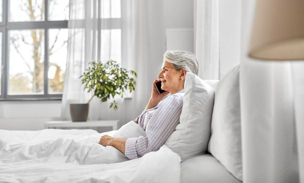 senior woman calling on smartphone in bed at home - Zdjęcie, obraz
