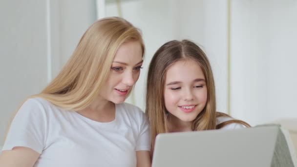 Μεσήλικη ενήλικη μητέρα και μαθήτρια έφηβη κόρη που κάθονται μαζί στο σπίτι κοιτάζοντας την οθόνη του φορητού υπολογιστή χρησιμοποιώντας υπολογιστή βλέποντας ταινία online surfing ιστοσελίδα περιήγηση ανάγνωση ειδήσεων - Πλάνα, βίντεο