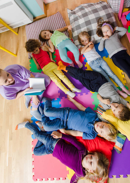 Active kids laying on soft pillows and mats at the kindergarten - Fotografie, Obrázek